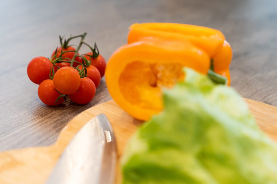 Tomatoes, lettuce and a yellow pepper on a chopping board