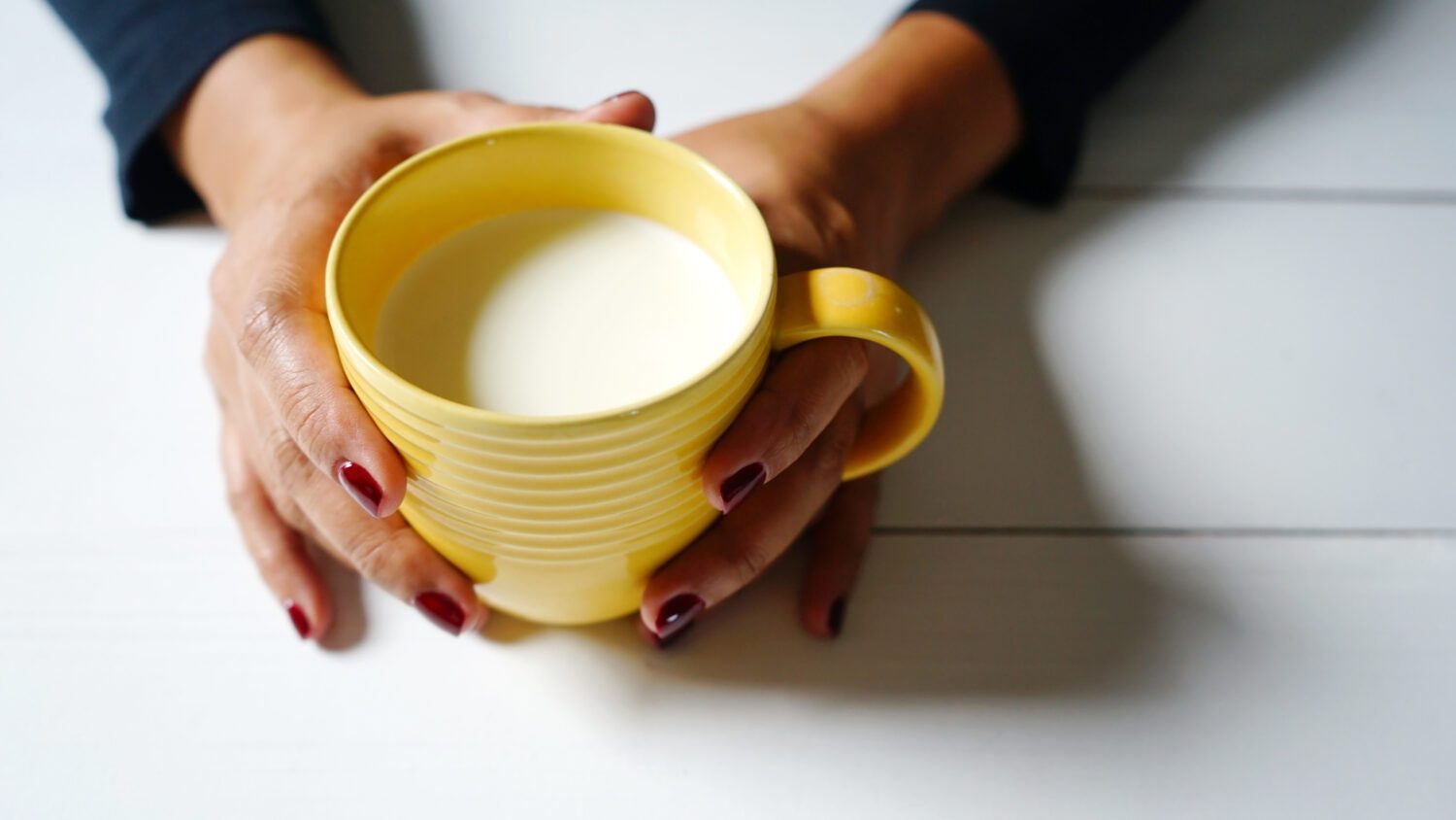 hands holding a mug of milk