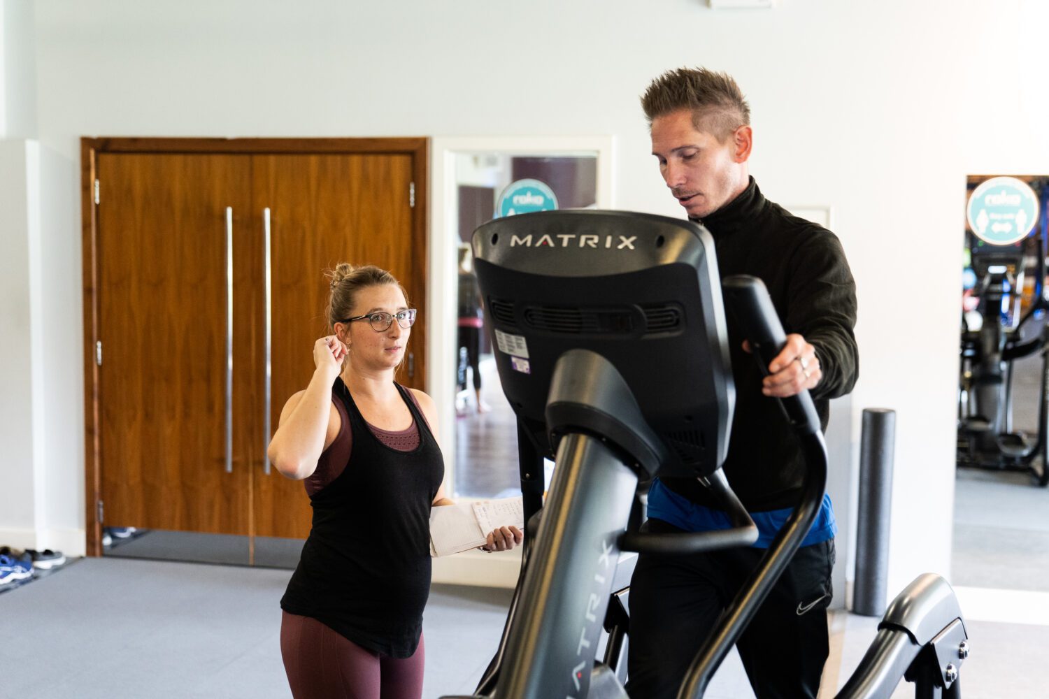 Personal trainer with client on a cross trainer