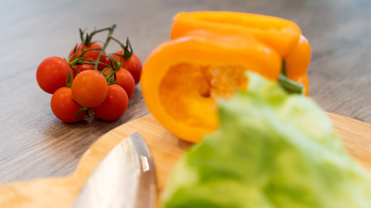 Tomatoes, lettuce and a yellow pepper on a chopping board