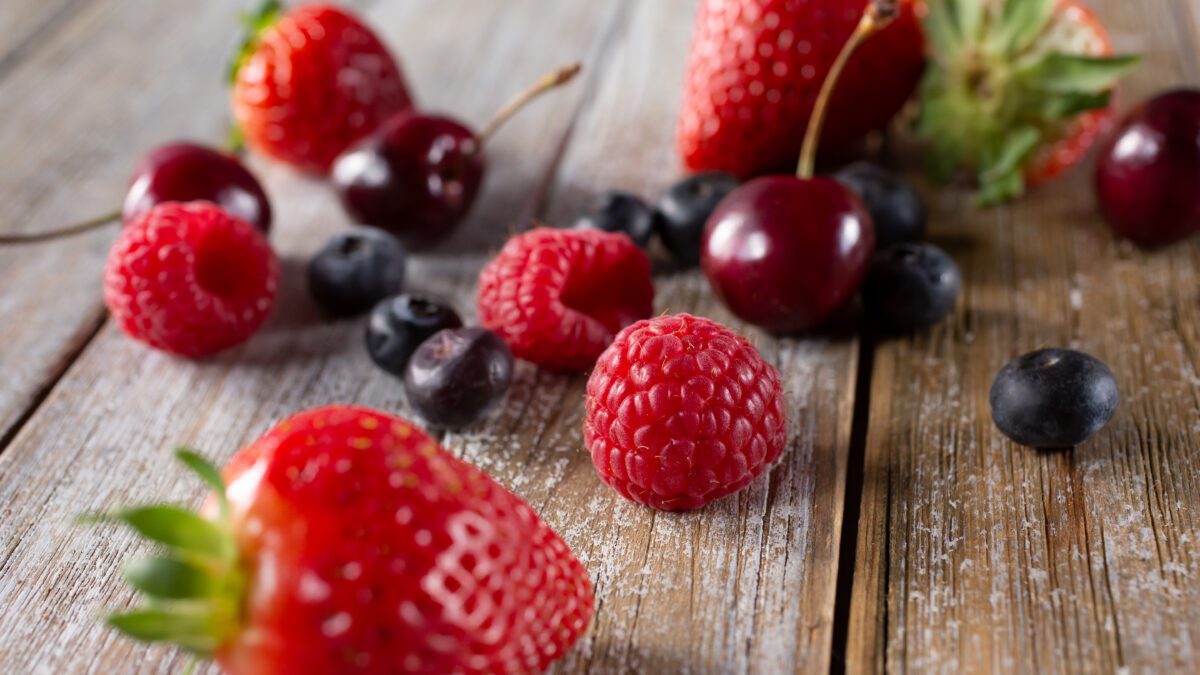 assorted red berries on a wooden surface