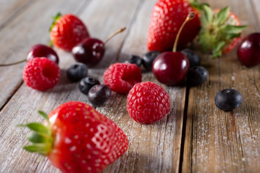 assorted red berries on a wooden surface