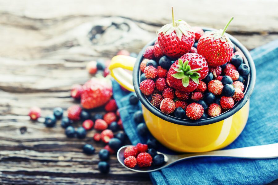 Red berries in a bowl on a wooden surface