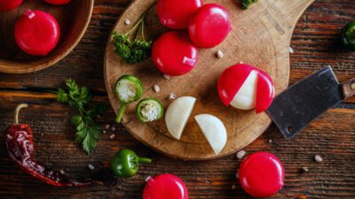 babybel cheeses opened on a board with a jalapeno pepper on the side