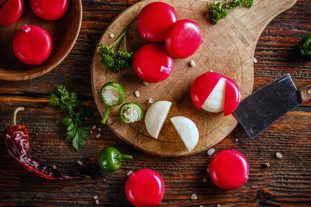 babybel cheeses opened on a board with a jalapeno pepper on the side