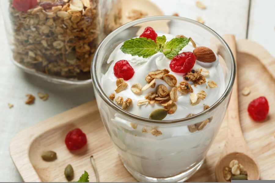 A bowl of yoghurt with red berries in it