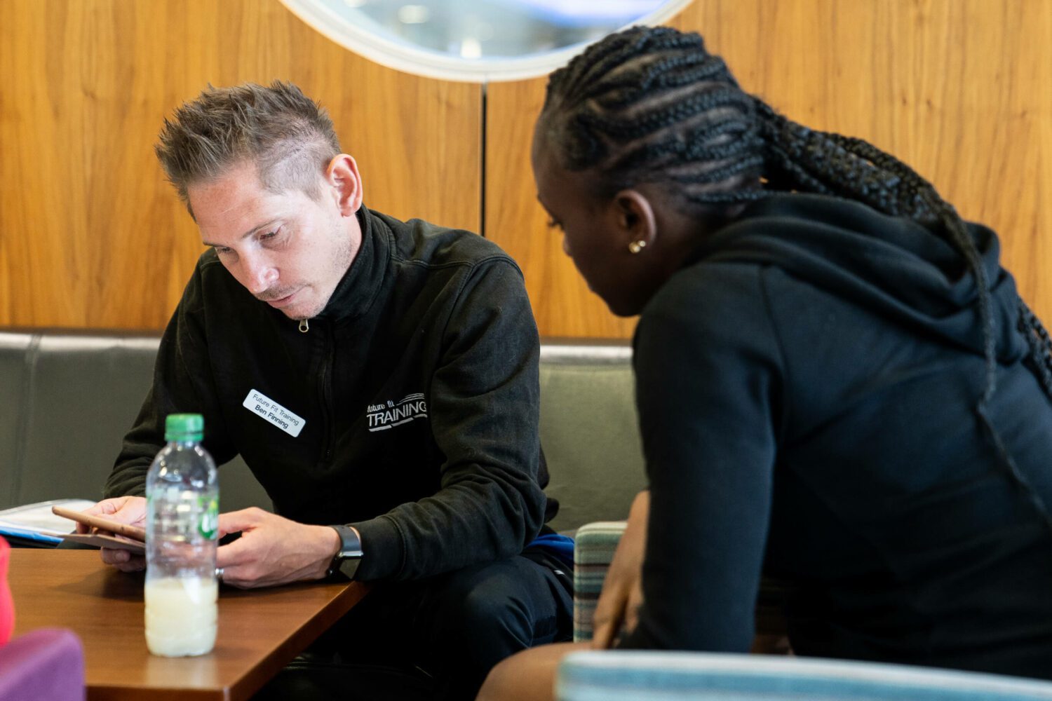 A student facing their tutor sitting opposite reading through a training manual