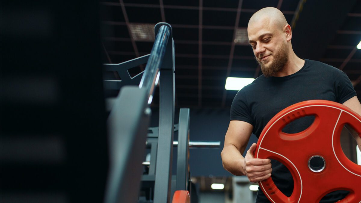 Personal trainer putting weights on barbell