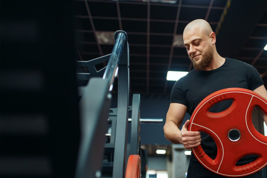 Personal trainer putting weights on barbell