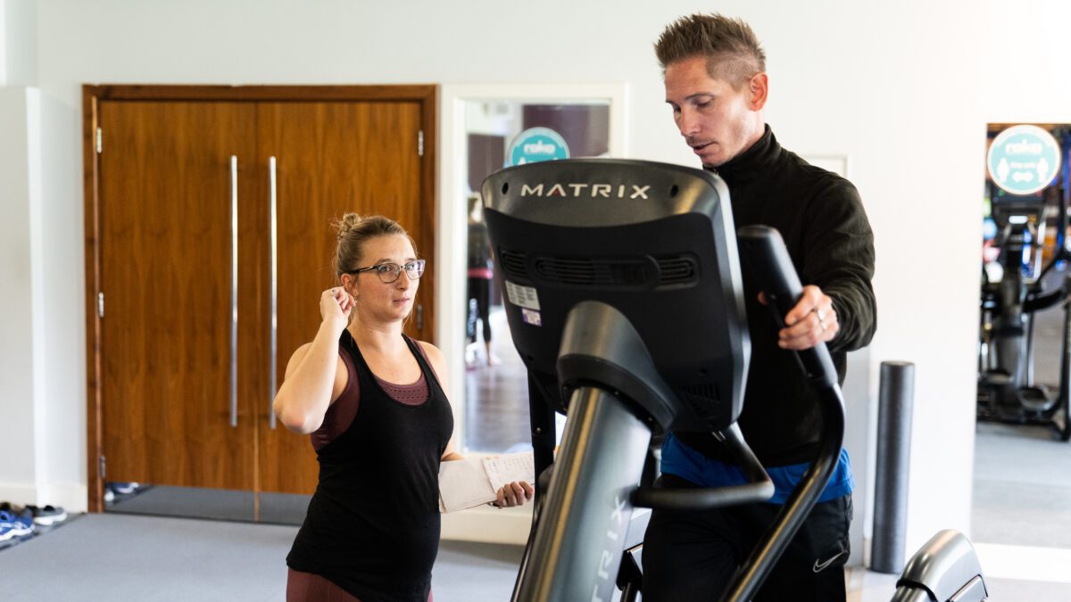 Personal trainer with client on a cross trainer