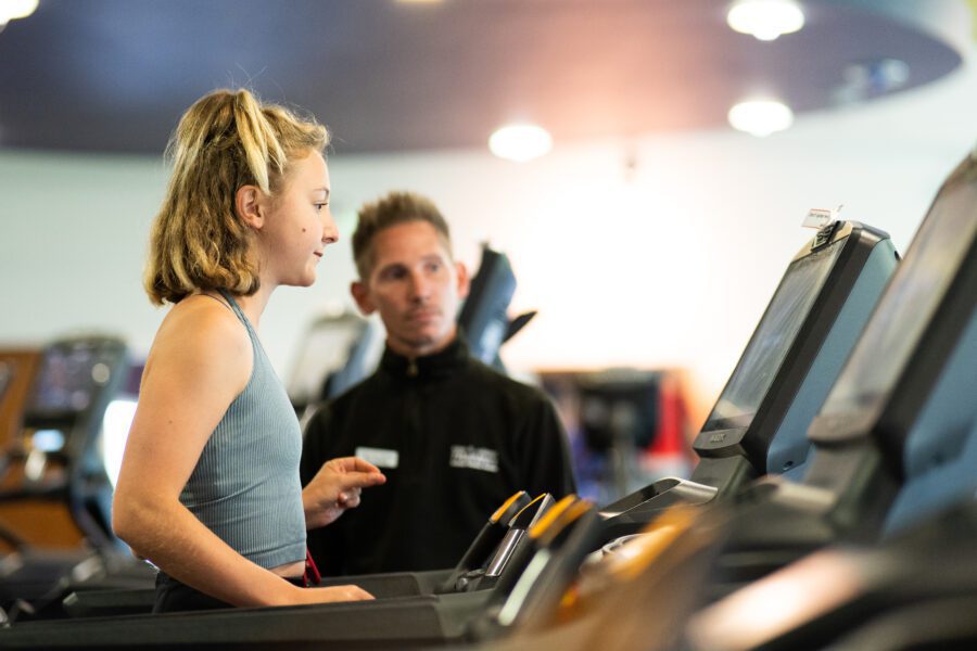 Personal trainer advising client on treadmill