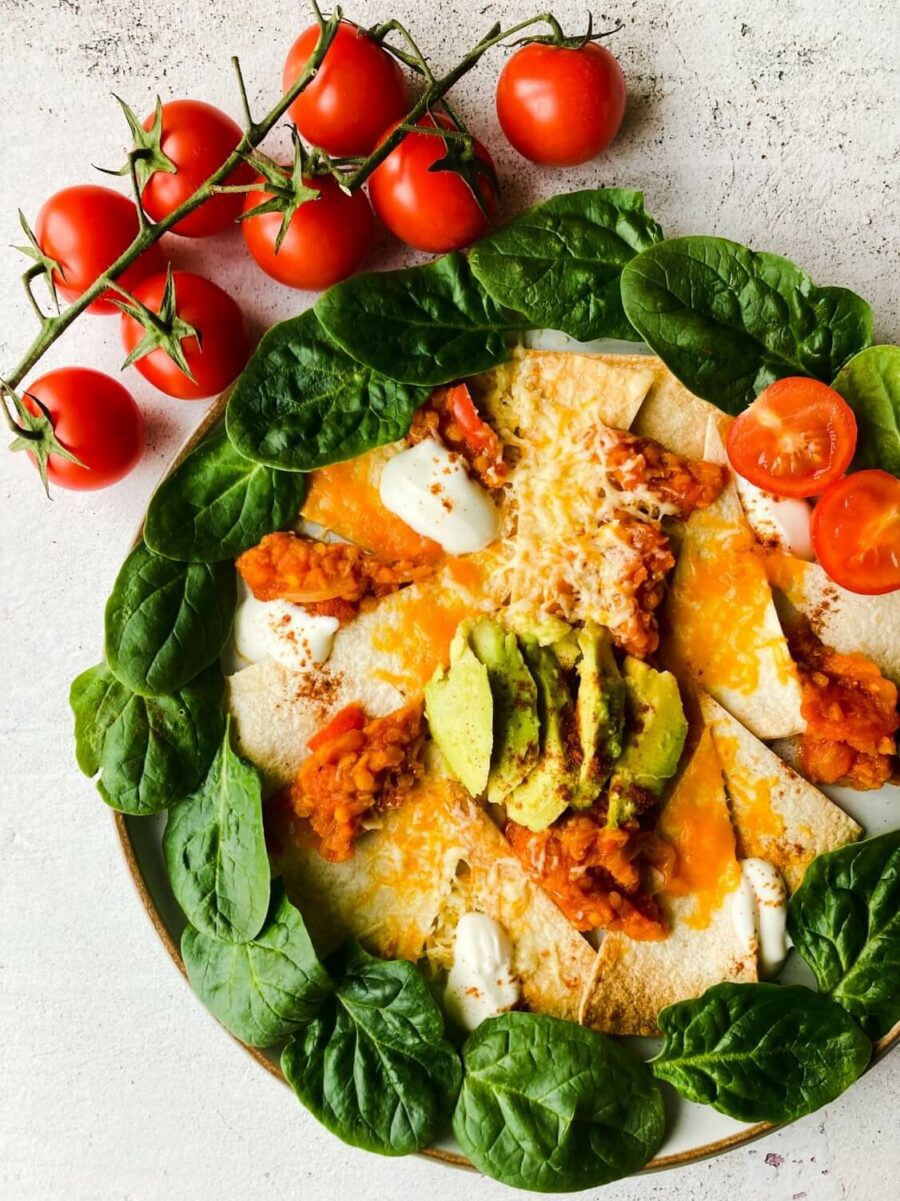 Plate of healthy nachos with green leafy veg and tomatoes on the side