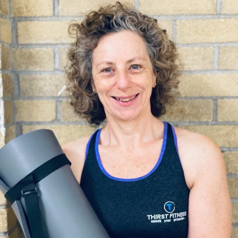 Karen Menis smiling, holding a yoga mat