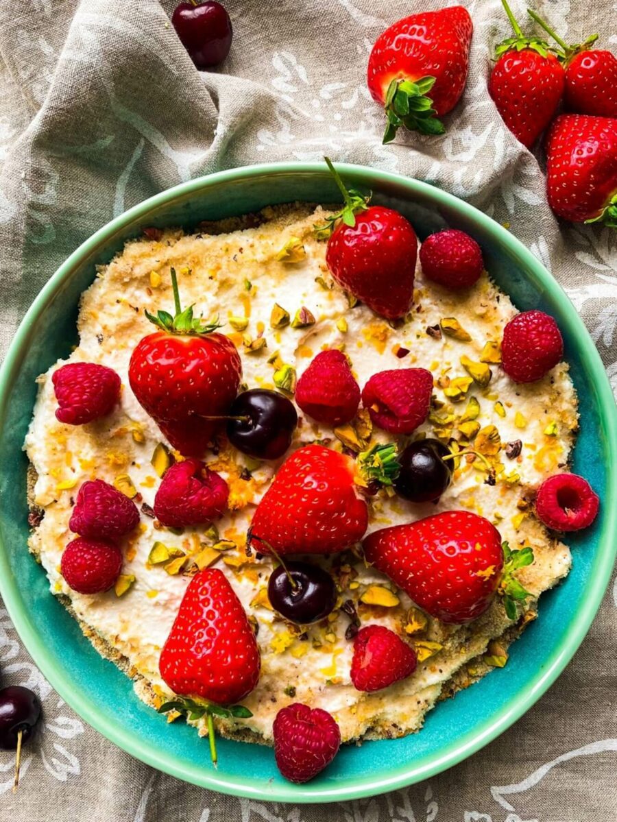 A over the top shot of the trifle in a blue bowl with strawberries and other summer berries on top