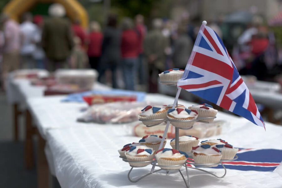 A side view of a table with a tiered display of cupcakes with a union flag on the top