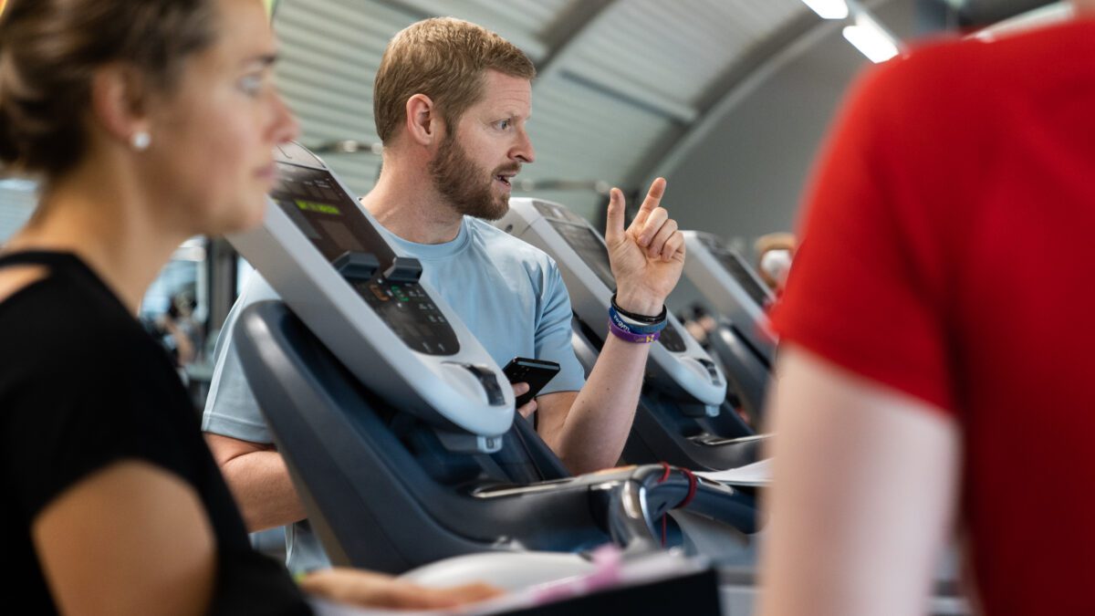 A personal trainer is instructing two people in the gym