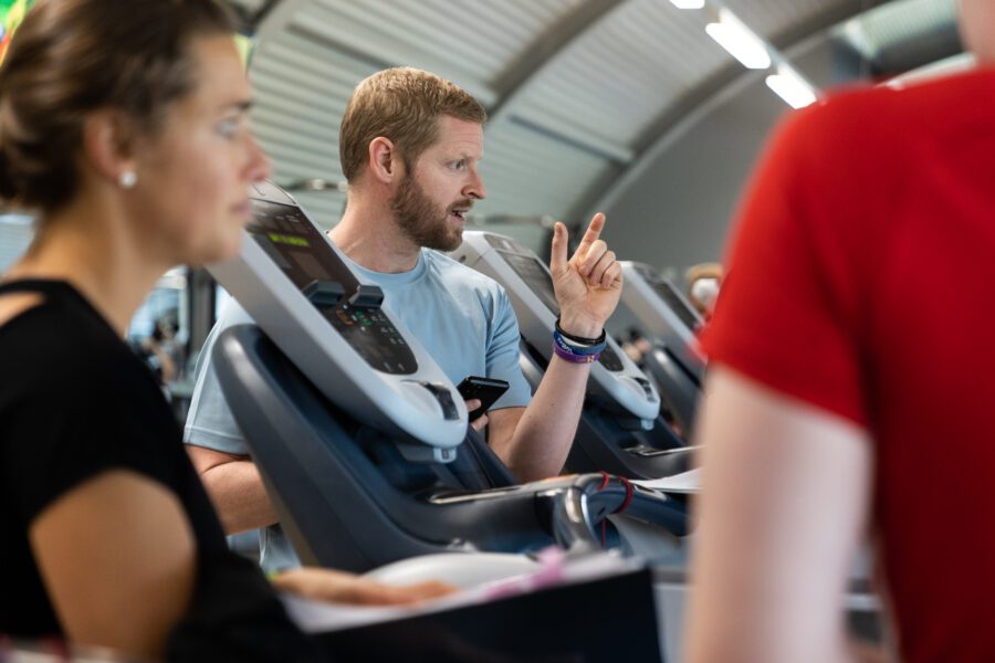 A personal trainer is instructing two people in the gym