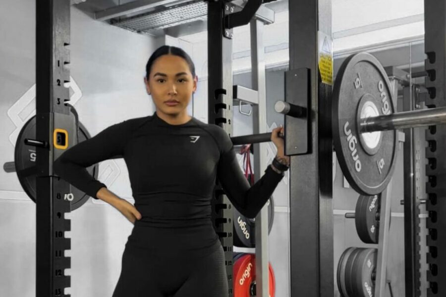 A woman standing in a squat rack holding a barbell