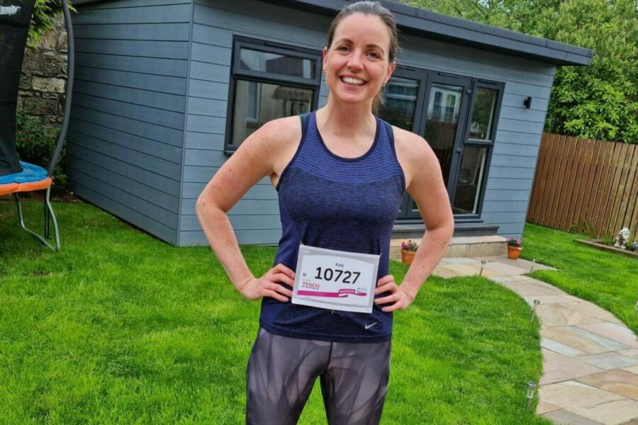 A woman standing in her garden in front of a shed wearing running clothes