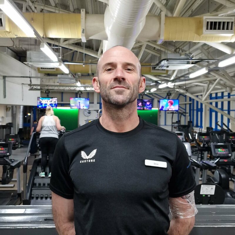 A man standing in a gym with his hands behind his back