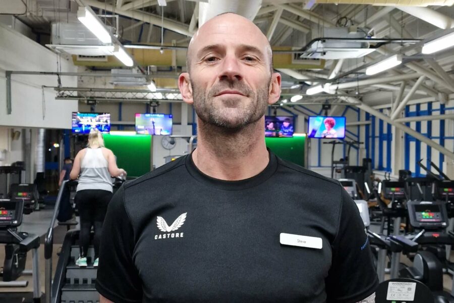 A man standing in a gym with his hands behind his back