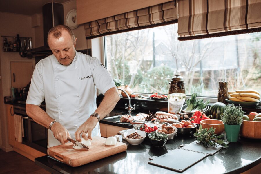 Elevated Food For Life, Jason Shaw - in chef's whites chopping food.