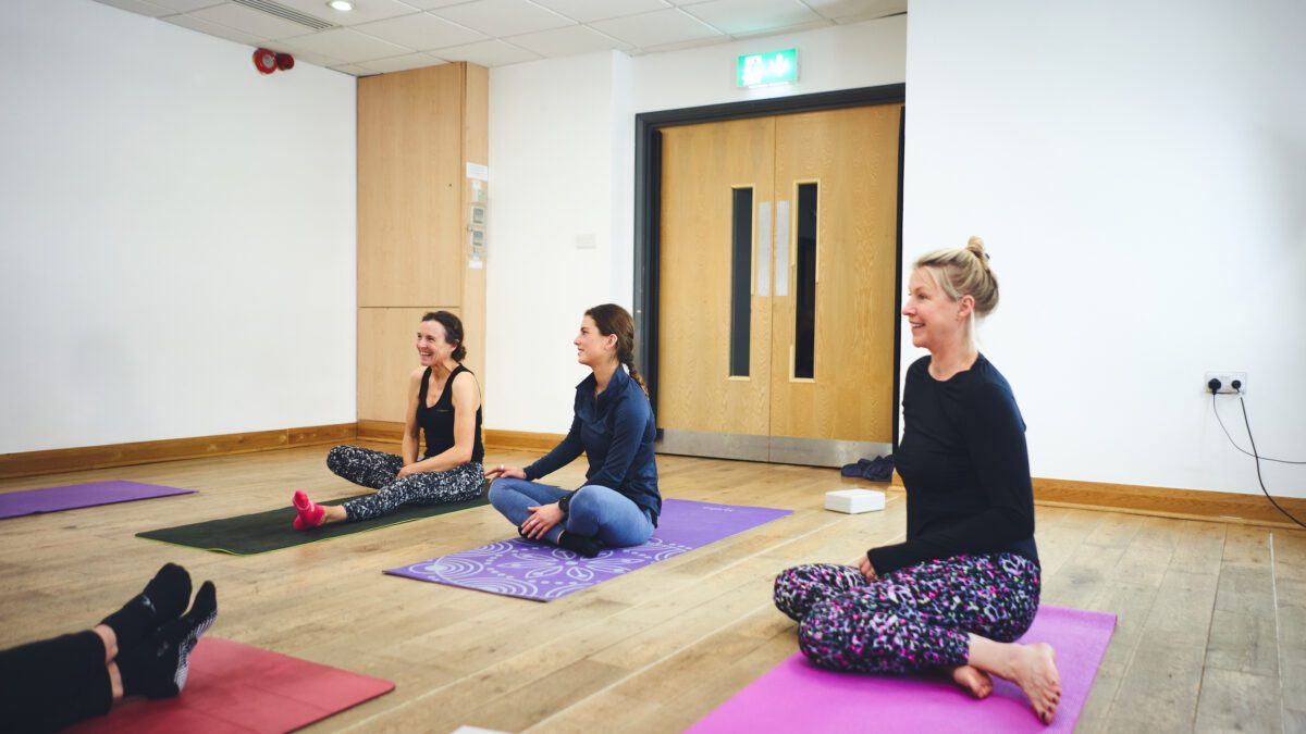 three women smiling on pilates mats