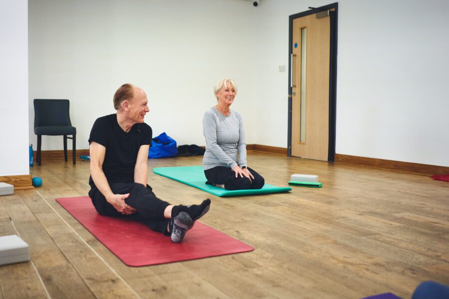 man and women sat on pilates mats