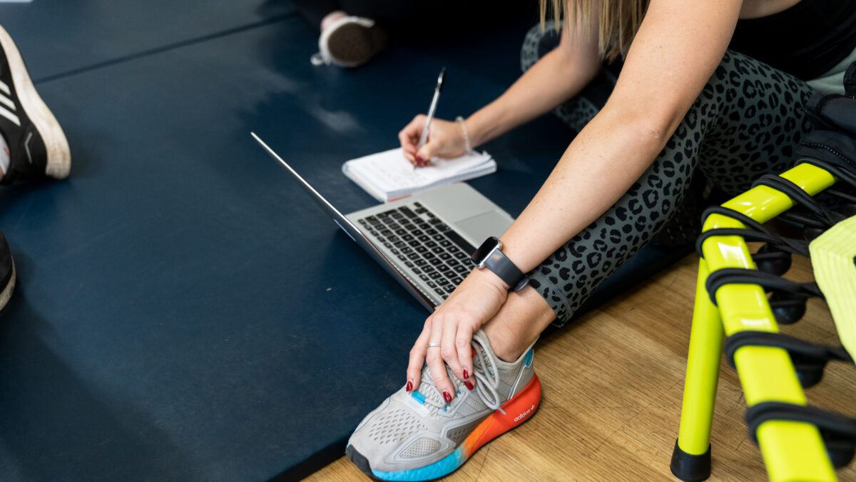 A woman taking notes on a notepad next to a laptop