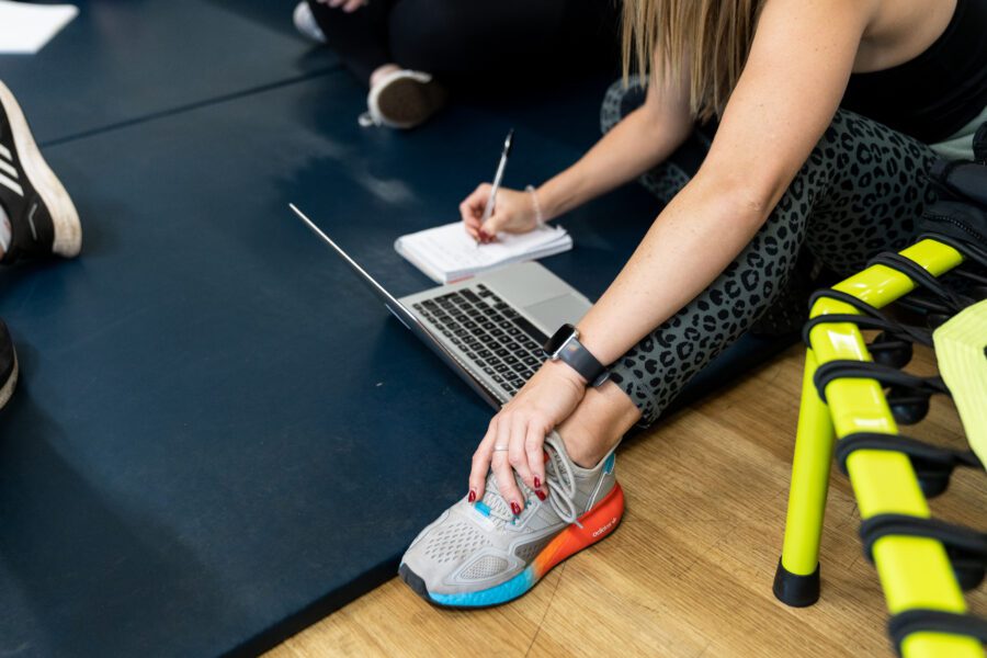 A woman taking notes on a notepad next to a laptop