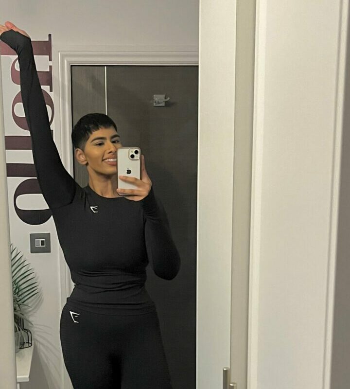 A woman standing in a doorway in exercise clothes
