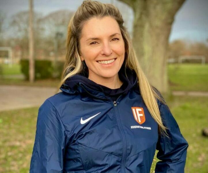 Young woman with blonde hair wearing a sports jacket smiling at the camera