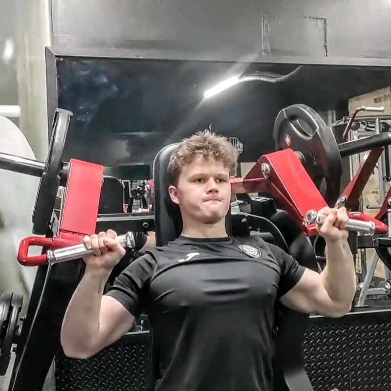 A young man in the gym using a weights machine